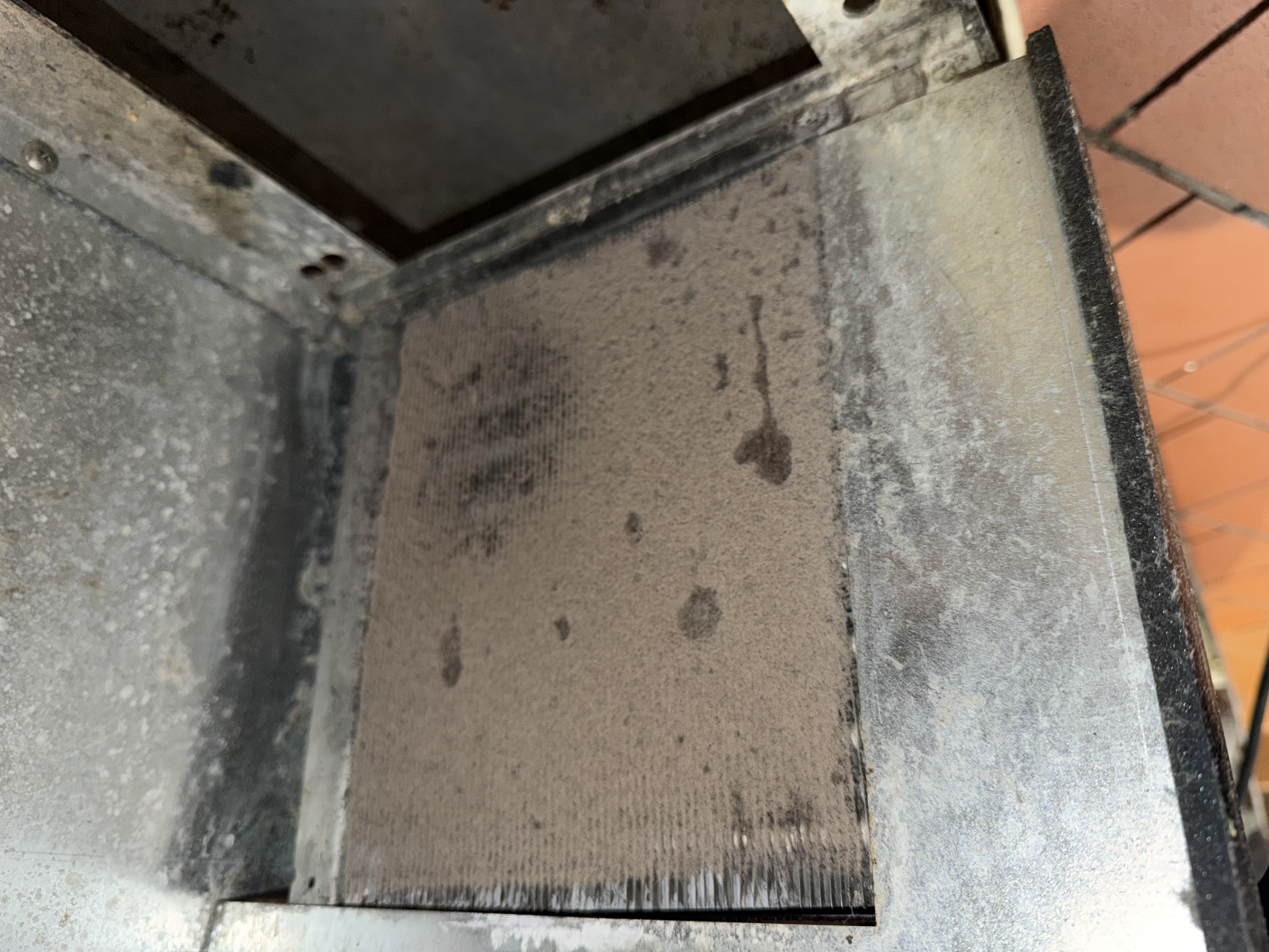 Before cleaning on a reach-in cooler, showing heavy buildup on the filter and coil section during a restaurant maintenance visit